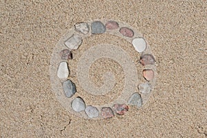 Round frame made of pebble stones on sand background