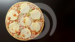 Round frozen pizza. Tomatoes, mozzarella, pesto, basil. Anthracite background. photo