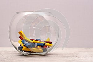 A round glass jar with colored notes of craft paper. Light background.