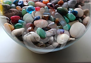 Round glass jar full of colorful quartz gemstones and sea pebbles