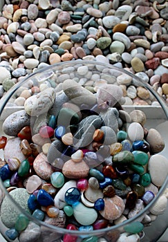 Round glass vase with colored minerals and flat box with sea stones top view