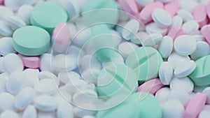 Round green and pink medicines lie with white antiviral pills. Rotation