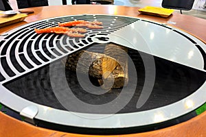 Round grill surrounded by a wooden dining table