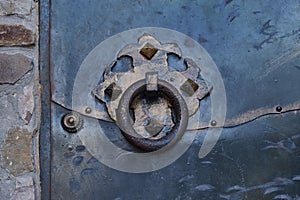 Round handle of an old wrought iron rusty door in a medieval fortress.