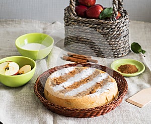 Round homemade cinnamon apple pie in a wicker plate