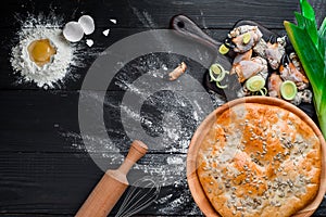 Round homemade pie with crab meat on a black wooden background in a beautiful composition. top view. Space. Close-up