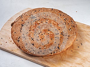 Round homemade wholegrain bread loaf on wooden kitchen board
