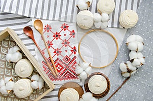 Round hoop frame, wooden spoons, meringue homemade zephyr in wooden tray, cotton buds and embroided napkin with traditional