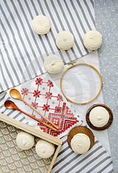 Round hoop frame, wooden spoons, meringue homemade zephyr in wooden tray and embroided napkin with traditional ornament. Mockup