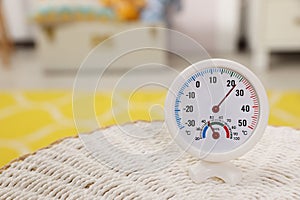 Round hygrometer with thermometer on mat in room. Space for text