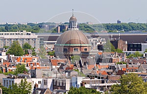 Round Koepelkerk with copper dome next to Singel canal . Roofs and facades of Amsterdam. City view from the bell tower