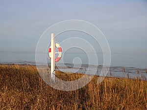 Round Lifesaver on White Pole at Ocean