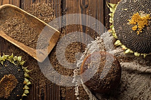 Round loaf of rye bread with thyme and ripe sunflowers on rustic style wooden table.