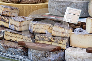 Round mature French Tomme goat cheese with cutted pieces on farmers market in France. English translation Cheese farm Notre Dame,