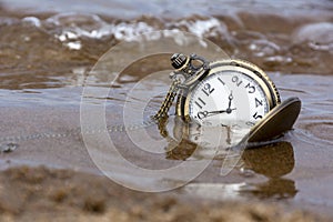 Round mechanical pocket watch on the sand under the water