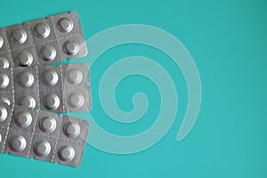 Round medical tablets in three packs, tablets packed in blisters on the left side with copyspace on blue background