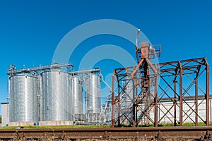 Round metal grain elevator bins next to railroad