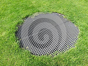 Round metal grid in a grass field above an airshaft