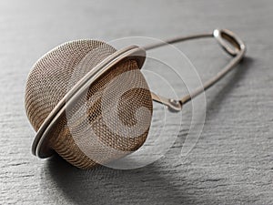 Round metal tea strainer for brewing tea on a black background