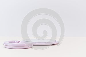 Round miror with pink frame on a bright beige desk against white wall