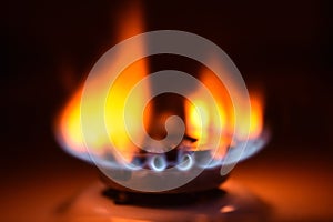 Round orange blue burning gas flame black background close up