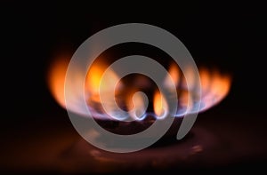 Round orange blue burning gas flame black background close up