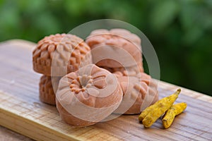 Round orange soap in the form of flowers with turmeric on a green background