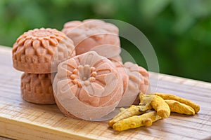 Round orange soap in the form of flowers with turmeric on a green background