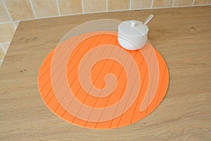 Round orange tablemat and sugar bowl on table