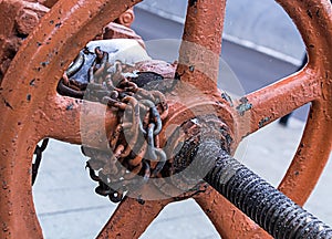 Round orange valve rusty old part of production long winding chain fixation in one position on a blurred background