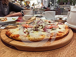 Round pide or Turkish pizza with cheese, sujuk and different types of meat on a wooden tray. selective focus. small focus area