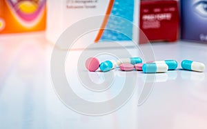 Round pink tablets pill and white-blue capsule pills on blurred background of drug packaging. Painkiller medicine. Drug use