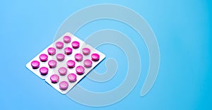 Round pink tablets pills in blister pack on blue background with space for text. Painkiller medicine. Online pharmacy and pharmacy