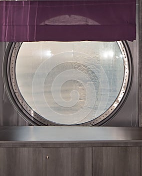 Round porthole of a sea cruise ship with water jets outside. Concept of sea travel