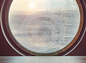 Round porthole of a sea cruise ship with water jets outside. Concept of sea travel