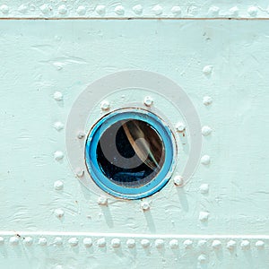 Round porthole on white board of ship