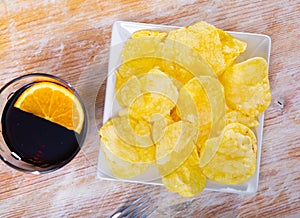 Round potato chips served in plate with a glass of vermouth