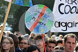 Round protest sign in the shape of planet earth saying `Save our planet` held up by young people during Global Climate Strike even