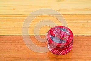 Round red gift box with ribbon bow on wooden table with copy spa