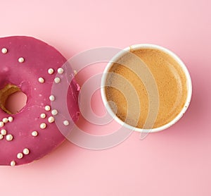 round red glazed donut and paper cup with coffee on a pink background