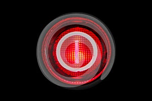 Round red power on and off button or switch with retro light illumination glowing in the dark macro photography