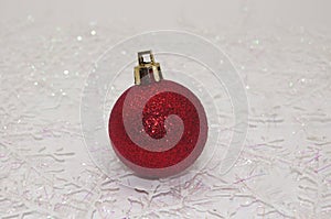 Round red sparkly Christmas ornaments on a table with snowflakes