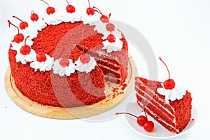 Round red velvet cake on a wooden plate decorated with canned cherries