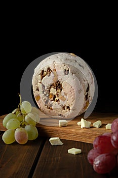 Round roquefort cheese with red grapes on a cutting board