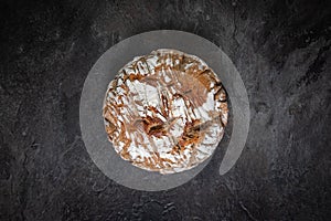 Round rustic bread on dark slate background in top-down studio setup