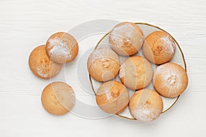 Round-shaped pastry, sprinkled with powdered sugar, on a plate. view from above