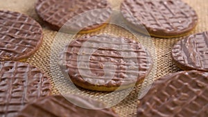 Round shortbread cookies coated with chocolate on a rustic burlap