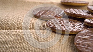 Round shortbread cookies coated with chocolate on a rustic burlap close-up