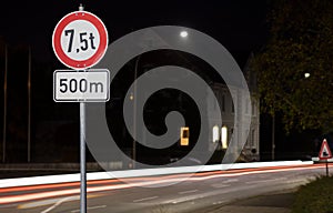 A round sign with lights at night. Only 7.5 tons of weight are allowed.