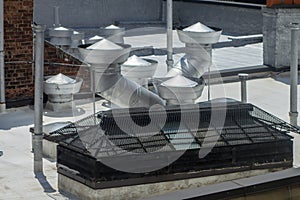 Round siver metal rooftop vents and ducts with rooftop skylight of a
